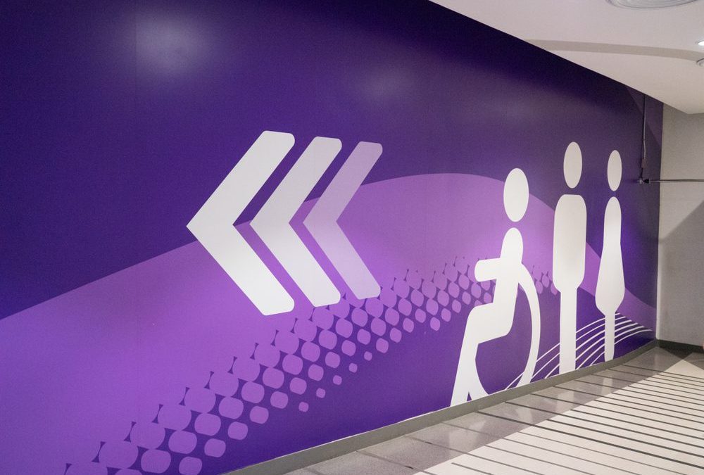 Toilet direction sign with triple arrow, painted on cement wall of department store, luxury shopping center, ultra violet tone.