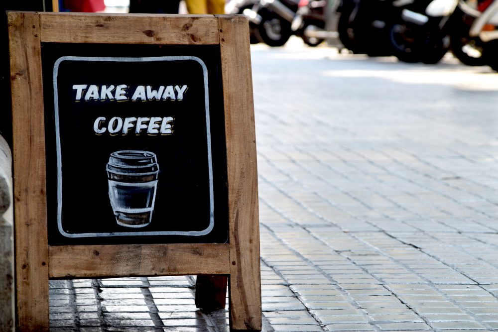 Take Away Coffee chalkboard sidewalk sign on cobblestone sidewalk